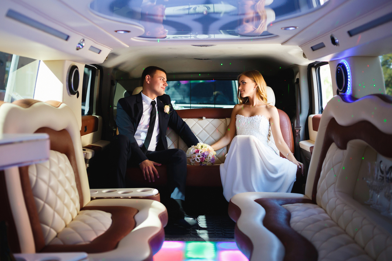 Newlyweds holding hands while inside their wedding transportation.